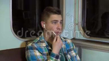 一个年轻<strong>人</strong>在地铁列车上通过耳机打电话。 旧地铁车